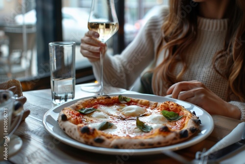Woman enjoying pizza and wine at table, fast food feast photo