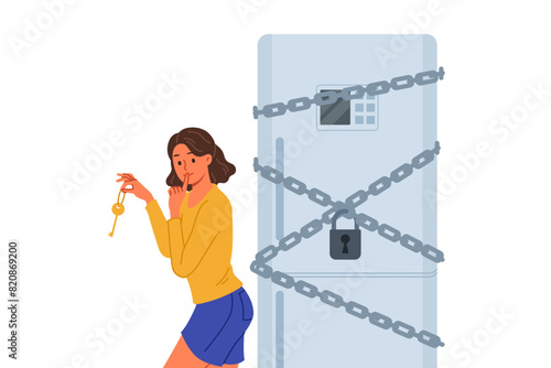 Woman starting diet locked refrigerator to reduce number of calories from food consumed. Funny girl wants to break diet and have dinner at night, due to lack of willpower and motivation