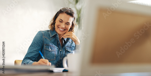 Happy businesswoman writing in her work diary at her office desk photo
