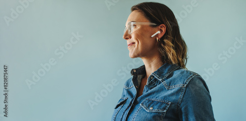 Focused and engaged: Businesswoman in denim jacket working with earphones in studio photo