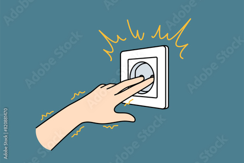 Hand near electrical outlet produces electric shock when touched due to violation of safety regulations. Man sticks fingers into socket and gets electric shock becouse of stupidity and curiosity