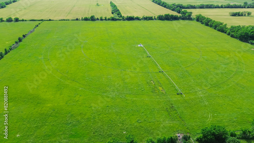 Center pivot irrigation on large farm grassland in Fairland, Oklahoma, stainless steel pipeline with mobile truss structures motorized wheels allowing pipe to move through the field, aerial view photo