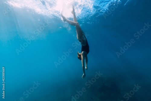 Woman dive to the sea bottom in blue ocean. Free diving with beautiful girl in ocean