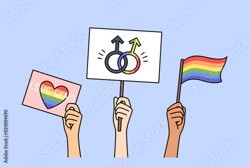 LGBT posters and flags in hands of people, with images of rainbow symbols and inscription love wins. LGBT community celebrates pride month and calls for fighting for rights of LGBTq individuals