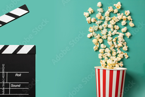 Popcorn with clapper board, film industry entertainment, tasty theater treat,green background, copy space