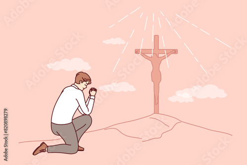 Businessman praying seeing christian cross on hill, worshiping lord and asking jesus for protection. Sunlight illuminates religious cross, to punish christian martyr who did not renounce religion