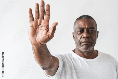 Handsome African American man showing a stop gesture with his palm outstretched to make a no or end gesture.