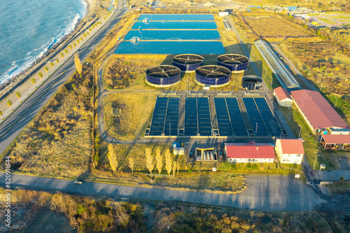 Aerial view of sewage treatment plant. Industrial water treatment with round water tanks for sewage recycling from drone view. Waste water management