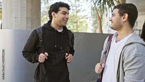 Two hispanic men chat amicably on a sunny urban street, portraying friendship and casual outdoor city life. photo