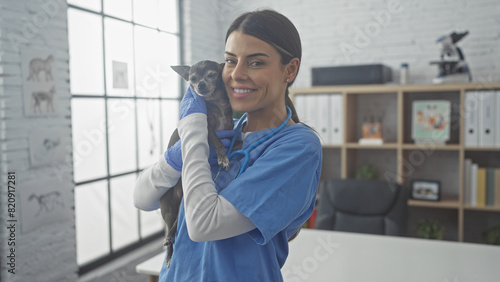 A smiling woman veterinarian holding a chihuahua in a clinic interior photo