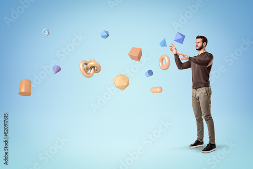 Young man standing and trying to manipulate geometric objects © gearstd