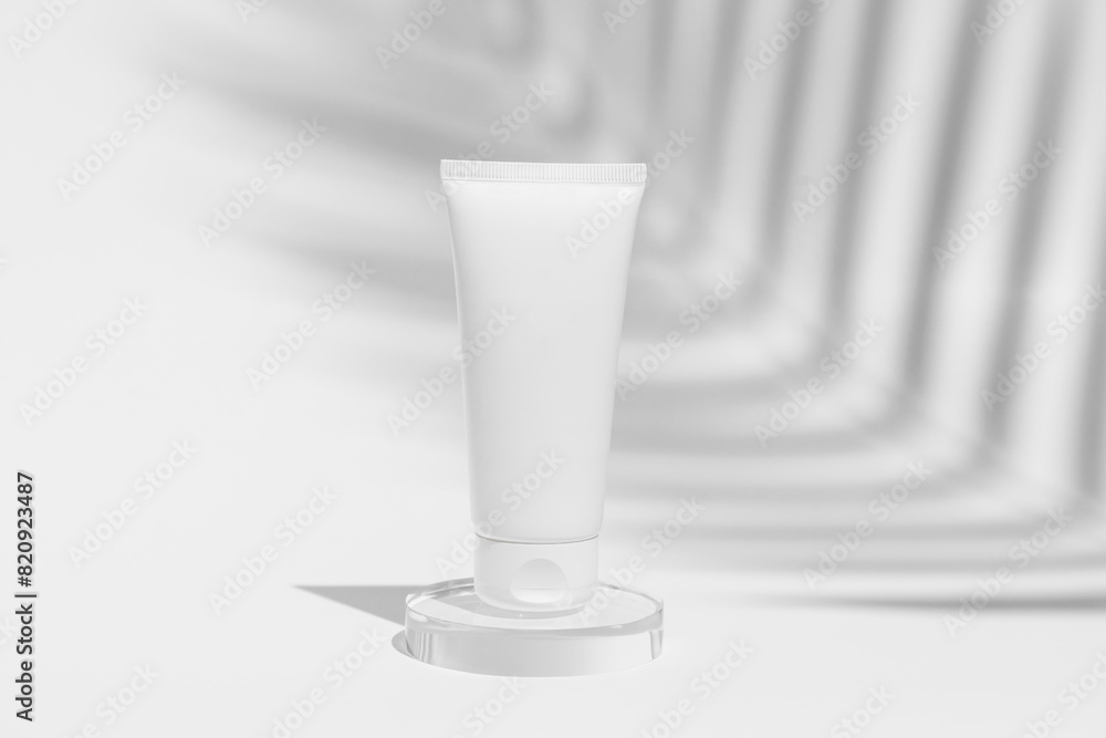 White face cream tube mockup on glass on white isolated background with shadow from palm tree. Natural cosmetics for skin care. White face cream tube mockup on glass on white isolated background with shadow from palm tree. Natural cosmetics for skin care.
