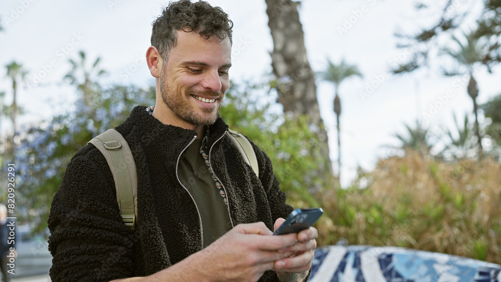 Handsome hispanic man with beard smiling while using smartphone on a sunny urban street. Handsome hispanic man with beard smiling while using smartphone on a sunny urban street.