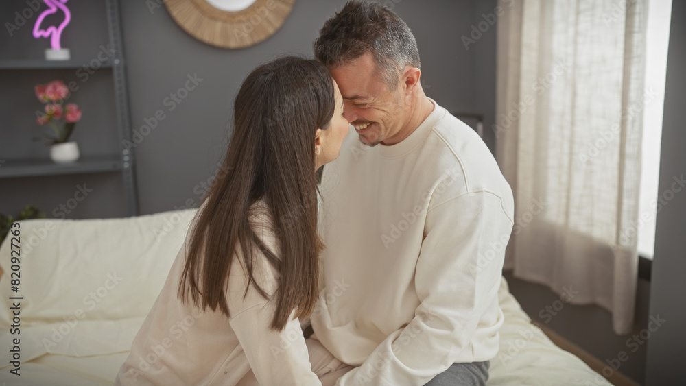 A loving couple embraces on a bed, enjoying a tender moment together in a cosy bedroom setting. A loving couple embraces on a bed, enjoying a tender moment together in a cosy bedroom setting.