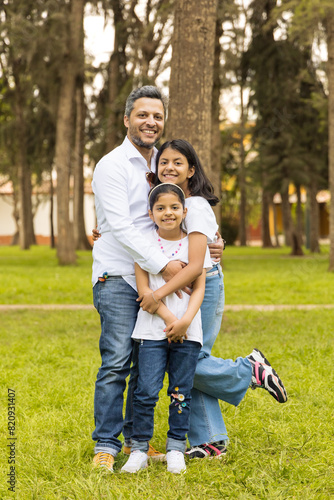 A family of three, a man and two children, are posing for a picture in a park