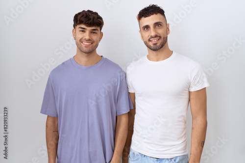 Homosexual gay couple standing over white background with a happy and cool smile on face. lucky person.