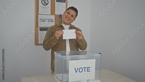 Photography A smiling hispanic man casting a ballot in a voting booth during an election