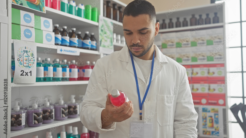 Hispanic man in white lab coat examining product at pharmacy with shelves of medication behind him