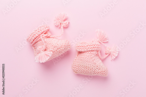 Pink baby booties on color background, top view