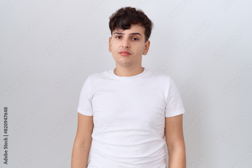 Young non binary man wearing casual white t shirt relaxed with serious expression on face. simple and natural looking at the camera. Young non binary man wearing casual white t shirt relaxed with serious expression on face. simple and natural looking at the camera.