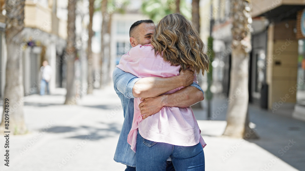 Fototapeta premium Man and woman couple hugging each other smiling at street