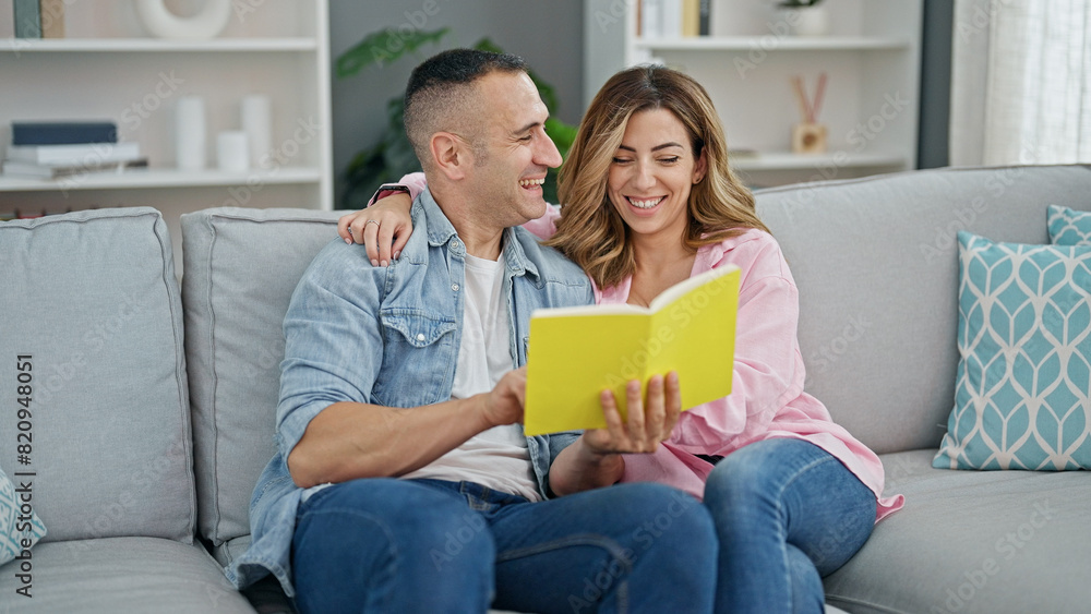 Man and woman couple reading book sitting on sof at home Man and woman couple reading book sitting on sof at home