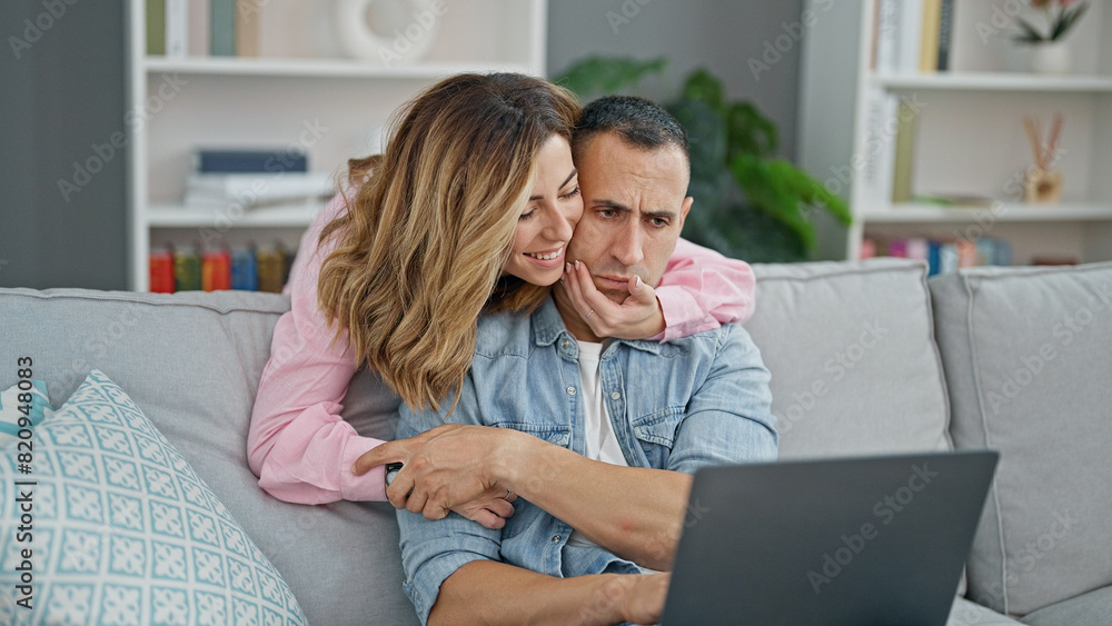 Man and woman couple using laptop sitting on sofa at home Man and woman couple using laptop sitting on sofa at home