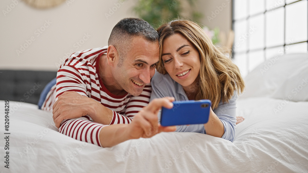 Man and woman couple lying on bed watching video on smartphone at bedroom Man and woman couple lying on bed watching video on smartphone at bedroom