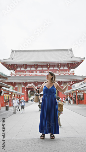 Joyful hispanic woman in glasses, with arms open, looking around senso-ji temple, tokyo with a beautiful smile embracing the carefree lifestyle. © Krakenimages.com