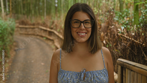 Joyful beautiful hispanic woman, casually posing with confident smile, glasses on, standing amidst the greenery of kyoto's bamboo forest © Krakenimages.com