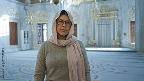 Obraz na plátně A young woman in a hijab stands contemplatively inside a stunning istanbul mosque with intricate islamic architecture