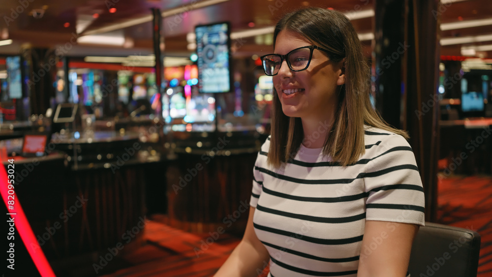 A smiling young adult hispanic woman enjoying herself at a lively casino environment, portraying leisure and entertainment. A smiling young adult hispanic woman enjoying herself at a lively casino environment, portraying leisure and entertainment.