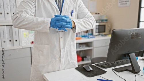 Asian man in lab coat and gloves standing in a laboratory with computer and scientific equipment