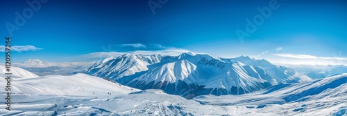 Expansive view of a snow-covered landscape with distant mountains under a bright blue sky.