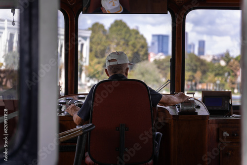 Adult male ferry captain in the wheelhouse is sailing along the route, rear view. photo