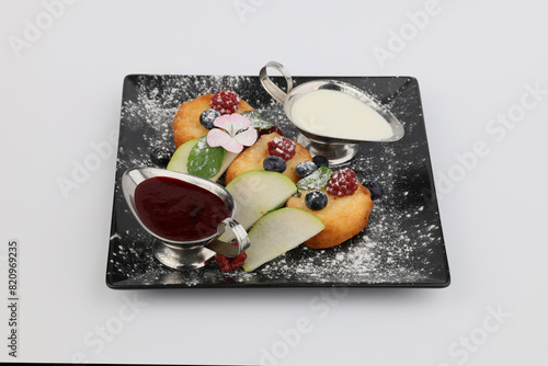 Syrnyky from cottage cheese with berry jam , sour cream and berry on dark plate on white background photo