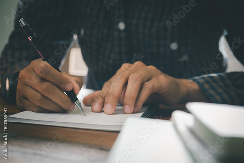 A student intensely studying and writing in a notebook, preparing for an upcoming exam in a university classroom setting, highlighting the importance of education and academic success photo