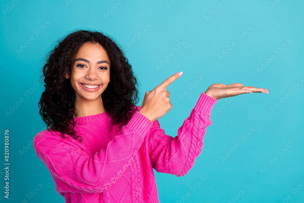 Portrait of nice young girl point finger arm hold empty space wear pink pullover isolated on turquoise color background Portrait of nice young girl point finger arm hold empty space wear pink pullover isolated on turquoise color background