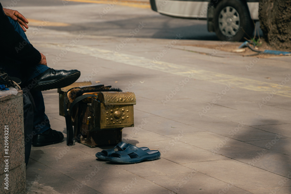 A part of a mobile shoe shine man is waiting on the side of the street A part of a mobile shoe shine man is waiting on the side of the street