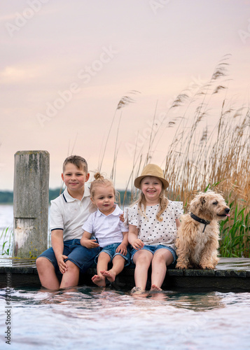 family having fun on the beach, kids sitting on the wooden pier near water