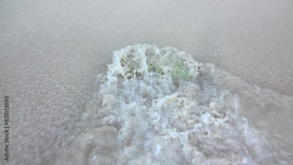 Breaking Wave Flows Around a Stone on a Sandy Beach. Slow Motion Breaking Wave Flows Around a Stone on a Sandy Beach. Slow Motion