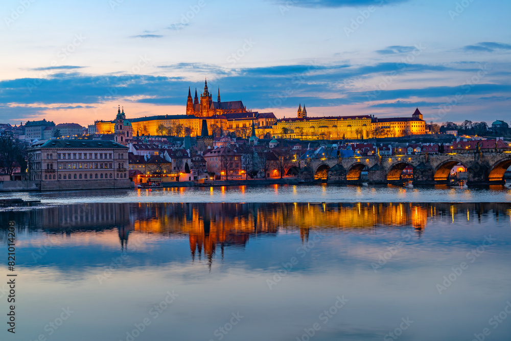 Fototapeta premium A picturesque evening view of the Prague additions - the Charles Bridge over the Vltava River and the illuminated Prague Castle with the Goitic Cathedral.