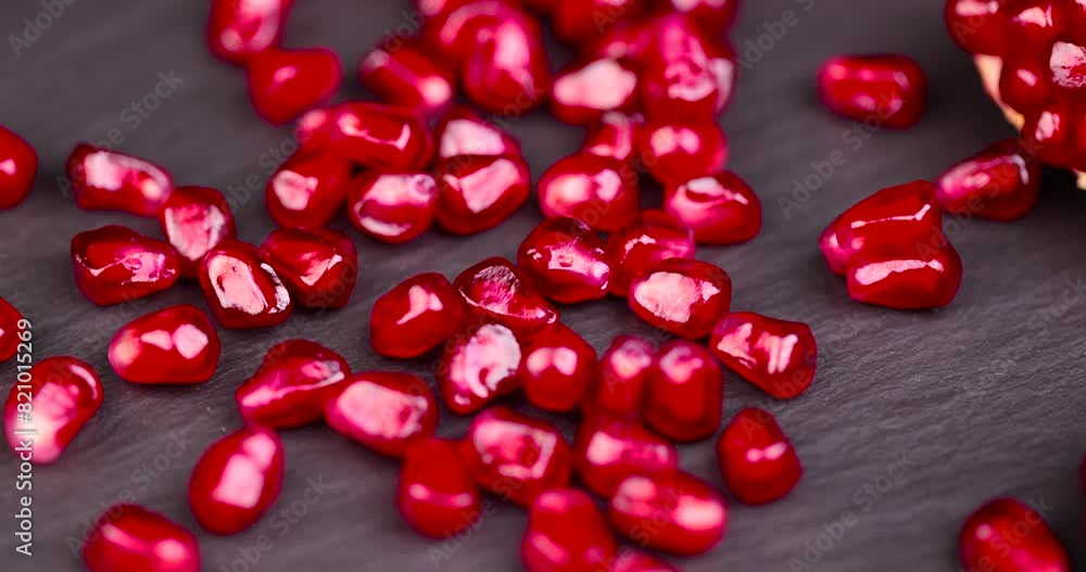 red grains of peeled pomegranate fruit, large sweet and juicy pomegranate seeds on a table made of black slate red grains of peeled pomegranate fruit, large sweet and juicy pomegranate seeds on a table made of black slate