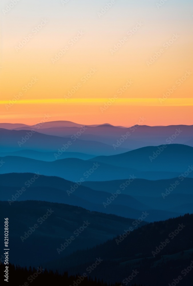 A beautiful sunrise over the mountains, with a clear blue sky and some silhouettes of hills in the background.