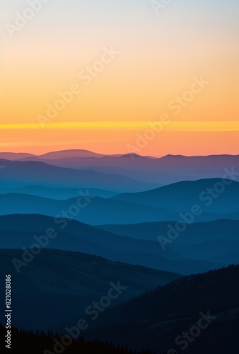 A beautiful sunrise over the mountains, with a clear blue sky and some silhouettes of hills in the background. © JH