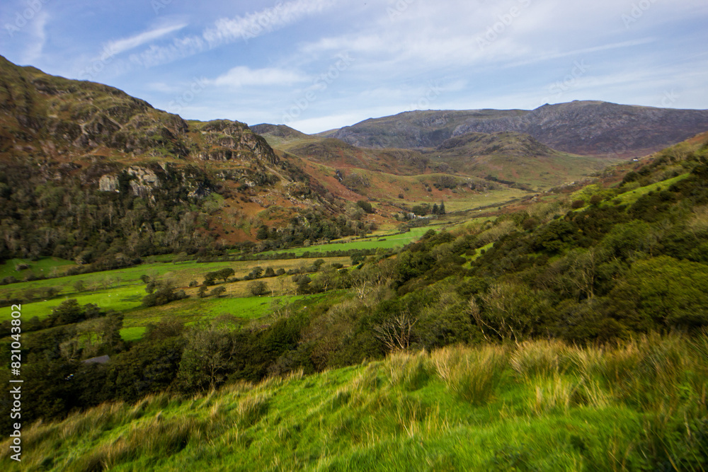 Spectacular view over the Nnant Gwynant valley in the mountains of Eryri National Park, filled with woodlands, farmland, and moorland on the mountain slopes