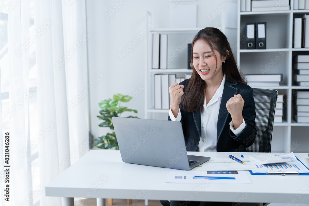 happy young businesswoman Asian siting on the chiar cheerful demeanor raise holding coffee cup smiling looking laptop screen.Making opportunities female working successful in the office. happy young businesswoman Asian siting on the chiar cheerful demeanor raise holding coffee cup smiling looking laptop screen.Making opportunities female working successful in the office.