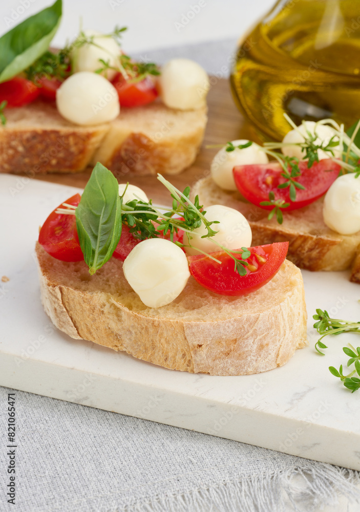 Round mozzarella, cherry tomatoes and microgreens on a piece of white bread Round mozzarella, cherry tomatoes and microgreens on a piece of white bread