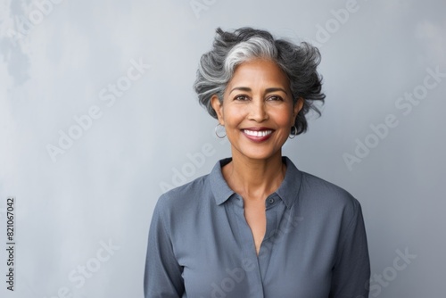 Portrait of a happy indian woman in her 60s with arms crossed isolated in minimalist or empty room background photo