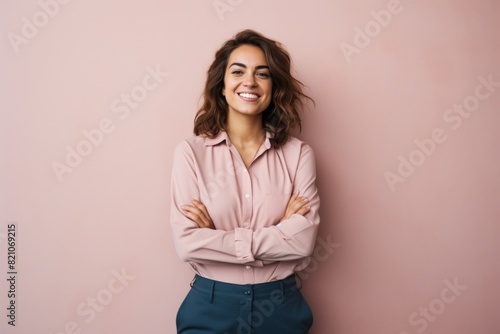 Portrait of a cheerful woman in her 20s with arms crossed isolated in minimalist or empty room background